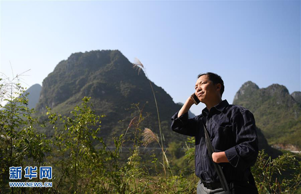 在上林县塘红乡古春村，黄立温在给贫困户打电话（11月1日摄）。